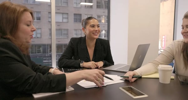 Women at a conference table, working and smiling
